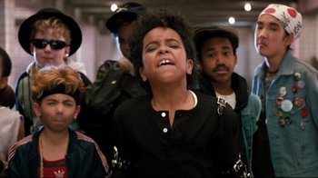 Movie still from “Moonwalker” (1988), directed by Jerry Kramer – A group of young people standing around a room; Close Up shot, Low angle