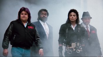 Movie still from “Moonwalker” (1988), directed by Jerry Kramer – A group of men standing next to each other; Medium shot, Low angle