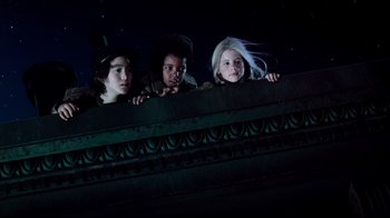 Movie still from “Moonwalker” (1988), directed by Jerry Kramer – Three children are looking over the top of a building; Medium shot, Low angle