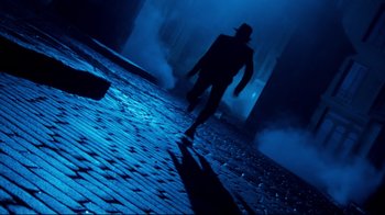 Movie still from “Moonwalker” (1988), directed by Jerry Kramer – A man in a fedora walking down a brick road at night; Wide shot, Low angle