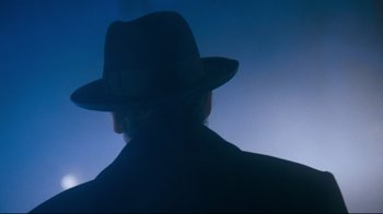 Movie still from “Moonwalker” (1988), directed by Jerry Kramer – A man wearing a hat and a black coat; Close Up shot, Low angle