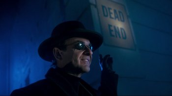 Movie still from “Moonwalker” (1988), directed by Jerry Kramer – A man wearing a hat and sunglasses in front of a dead end sign; Close Up shot, Low angle