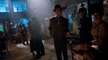 Movie still from “Moonwalker” (1988), directed by Jerry Kramer – A group of people standing around in a room; Wide shot, Low angle