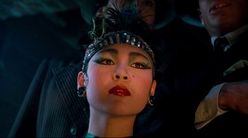 Movie still from “Moonwalker” (1988), directed by Jerry Kramer – A person wearing makeup and a feather headband; Close Up shot, Low angle