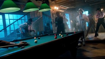 Movie still from “Moonwalker” (1988), directed by Jerry Kramer – A group of men playing a game of pool; Wide shot, High angle