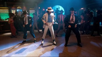 Movie still from “Moonwalker” (1988), directed by Jerry Kramer – A group of men in suits and hats dancing; Wide shot, High angle