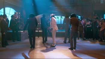 Movie still from “Moonwalker” (1988), directed by Jerry Kramer – A group of people standing around in a room; Wide shot, High angle