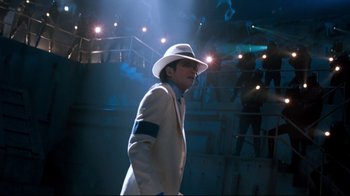 Movie still from “Moonwalker” (1988), directed by Jerry Kramer – A man in a white suit and a white hat; Medium shot, Low angle