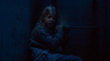 Movie still from “Moonwalker” (1988), directed by Jerry Kramer – A young girl sitting on the ground in a dark room; Medium shot, High angle