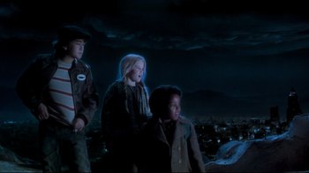 Movie still from “Moonwalker” (1988), directed by Jerry Kramer – A group of people standing on top of a hill at night; Medium shot, Low angle