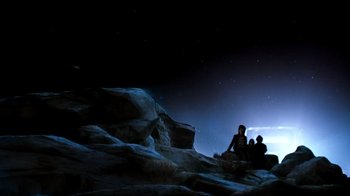 Movie still from “Moonwalker” (1988), directed by Jerry Kramer – A group of people sitting on top of a hill at night; Extreme Wide shot, Low angle