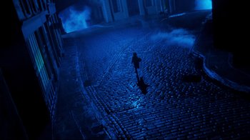 Movie still from “Moonwalker” (1988), directed by Jerry Kramer – A person standing on a brick road in the dark; Extreme Wide shot, High angle