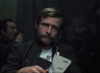 A man with a mustache holding a book in his hand