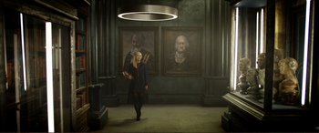 Movie still from “Mortal Engines” (2018), directed by Christian Rivers – A woman walking in front of two paintings; Wide shot, Low angle