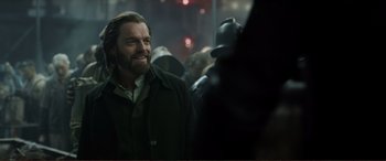 Movie still from “Mortal Engines” (2018), directed by Christian Rivers – A man that is standing in a crowd of people; Close Up shot, Over the shoulder angle