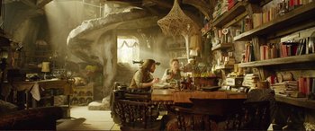 Movie still from “Mortal Engines” (2018), directed by Christian Rivers – A man and woman sitting at a table in a room; Wide shot, Low angle