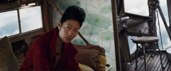 Movie still from “Mortal Engines” (2018), directed by Christian Rivers – A person with a red jacket sitting in a room; Close Up shot, Over the shoulder angle