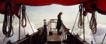 Movie still from “Mortal Engines” (2018), directed by Christian Rivers – A woman standing on a wooden deck looking out at the ocean; Wide shot, High angle