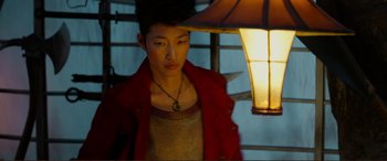 Movie still from “Mortal Engines” (2018), directed by Christian Rivers – A young man wearing a red jacket standing next to a lamp; Close Up shot, Low angle