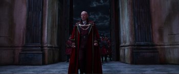 Movie still from “Mortal Engines” (2018), directed by Christian Rivers – A man in a red robe and a red hat standing in front of a group of soldiers; Wide shot, Low angle