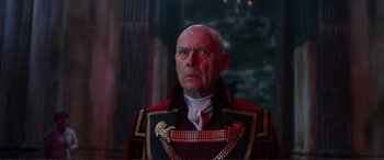 Movie still from “Mortal Engines” (2018), directed by Christian Rivers – A man in a red and black uniform looking at the camera; Close Up shot, Low angle