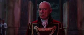 Movie still from “Mortal Engines” (2018), directed by Christian Rivers – A man in a red and black uniform looking to his left; Close Up shot, Low angle