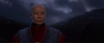 Movie still from “Mortal Engines” (2018), directed by Christian Rivers – An older man wearing a red and blue outfit; Close Up shot, Low angle