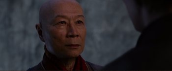Movie still from “Mortal Engines” (2018), directed by Christian Rivers – An older asian man looking into the distance; Close Up shot, Over the shoulder angle