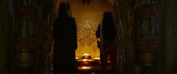 Movie still from “Mortal Engines” (2018), directed by Christian Rivers – Two women standing in front of a statue with candles; Close Up shot, Over the shoulder angle