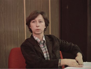 Movie still from “Moscow Does Not Believe in Tears” (1980), directed by Vladimir Menshov – A person sitting in a chair wearing a jacket; Close Up shot, Low angle