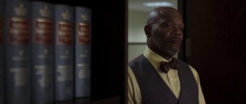 Movie still from “Mother and Child” (2009), directed by Rodrigo García – A man in a bow tie standing in front of a book case; Close Up shot, Low angle