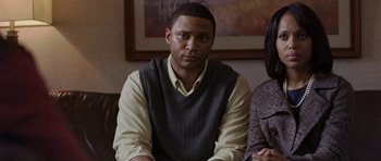 Movie still from “Mother and Child” (2009), directed by Rodrigo García – A man sitting in front of a woman in front of a painting; Close Up shot, High angle