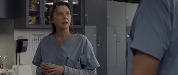 Movie still from “Mother and Child” (2009), directed by Rodrigo García – A woman in scrubs holding a cup in a room; Close Up shot, Over the shoulder angle