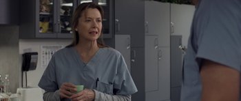 Movie still from “Mother and Child” (2009), directed by Rodrigo García – A woman in scrubs holding a cup in a room; Close Up shot, Over the shoulder angle