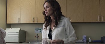 Movie still from “Mother and Child” (2009), directed by Rodrigo García – A woman in a white lab coat standing in a kitchen; Medium shot, Over the shoulder angle