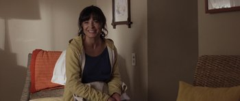 Movie still from “Mother and Child” (2009), directed by Rodrigo García – A woman sitting in a room smiling for the camera; Medium shot, High angle