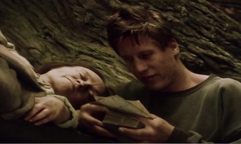 Movie still from “Mother and Son” (1997), directed by Aleksandr Sokurov – A man holding a book while another man looks at it; Close Up shot, High angle