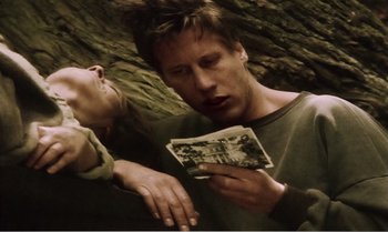 Movie still from “Mother and Son” (1997), directed by Aleksandr Sokurov – A man and a woman are looking at old photos; Medium shot, Low angle
