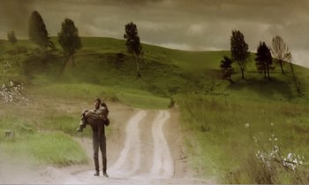 Movie still from “Mother and Son” (1997), directed by Aleksandr Sokurov – A man carrying a woman on his back on a dirt road; Extreme Wide shot, Low angle