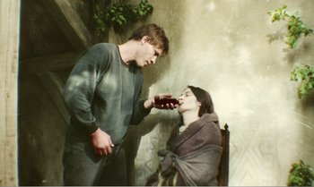 Movie still from “Mother and Son” (1997), directed by Aleksandr Sokurov – A young man feeding a woman a chocolate bar; Medium shot, Low angle