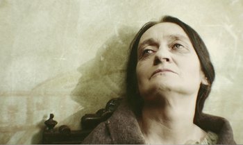 Movie still from “Mother and Son” (1997), directed by Aleksandr Sokurov – An older woman is laying on the ground; Close Up shot, High angle