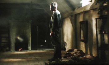 Movie still from “Mother and Son” (1997), directed by Aleksandr Sokurov – A man standing in a room with a lot of debris; Wide shot, Low angle