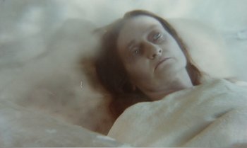 Movie still from “Mother and Son” (1997), directed by Aleksandr Sokurov – A woman laying in a bed with her eyes closed; Close Up shot, High angle