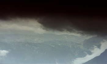 Movie still from “Mother and Son” (1997), directed by Aleksandr Sokurov – A view of a mountain range with a dark sky above it; Extreme Wide shot, High angle