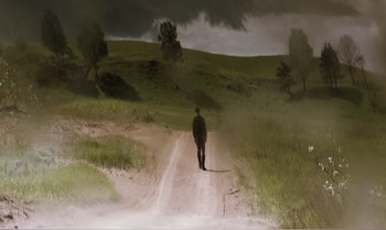 Movie still from “Mother and Son” (1997), directed by Aleksandr Sokurov – A man walking down a dirt road on a cloudy day; Extreme Wide shot, Low angle