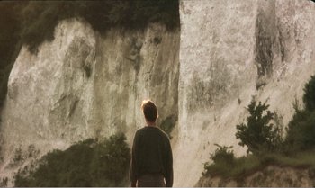 Movie still from “Mother and Son” (1997), directed by Aleksandr Sokurov – A man standing in front of a cliff; Extreme Wide shot, Low angle
