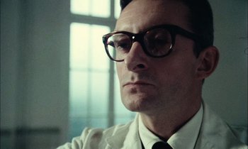 Movie still from “Mr. Klein” (1976), directed by Joseph Losey – A person wearing glasses and a tie; Close Up shot, Low angle