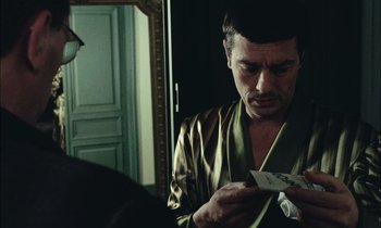 Movie still from “Mr. Klein” (1976), directed by Joseph Losey – A man in a dressing gown looking at a deck of playing cards; Close Up shot, Over the shoulder angle