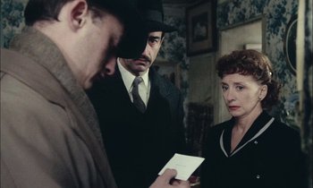 Movie still from “Mr. Klein” (1976), directed by Joseph Losey – A group of people standing next to each other in a room; Medium shot, Over the shoulder angle