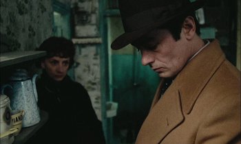Movie still from “Mr. Klein” (1976), directed by Joseph Losey – A man wearing a hat and a coat looking down at a woman; Close Up shot, Over the shoulder angle